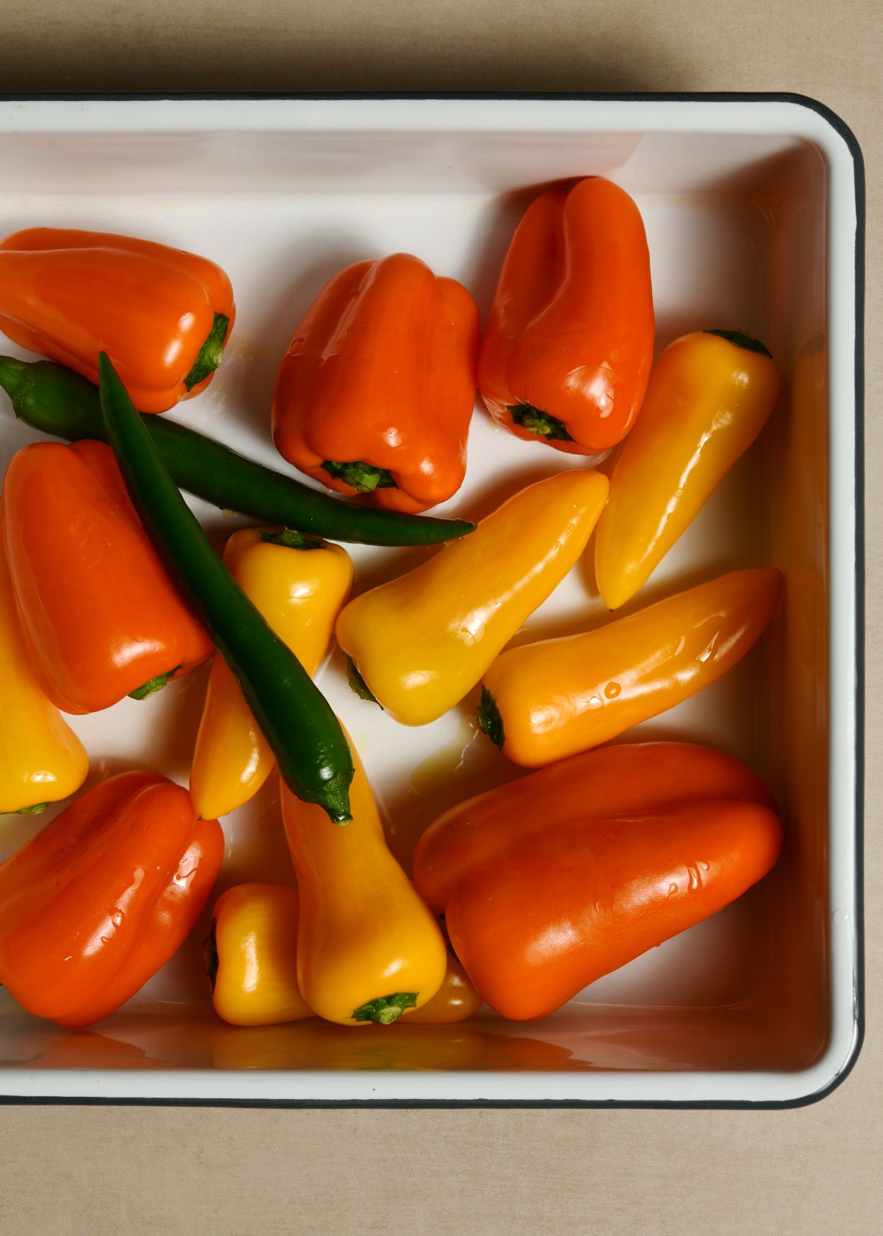 წიწაკები გავრეცხოთ, გავამშრალოთ, ჩავყაროთ საცხობ ყალიბში და ფუნჯით გადავუსვათ ზეთი.